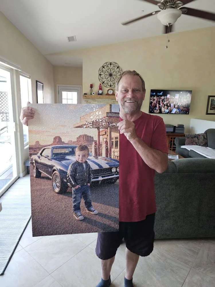 A smiling grandfather holding up his finished custom photo puzzle of his grandson posing with a classic muscle car